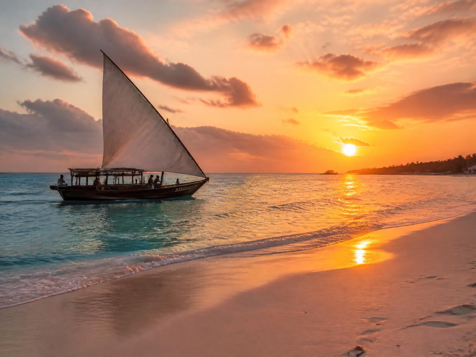 A traditional dhow sailing off a Zanzibar beach at sunset
